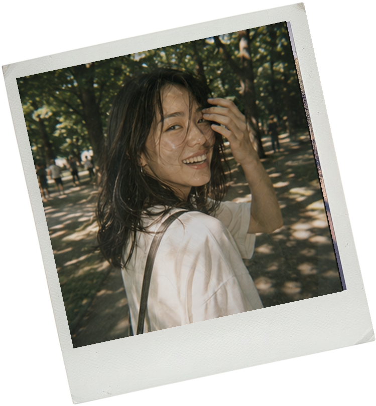 An instant photo of a woman smiling in dappled sunlight